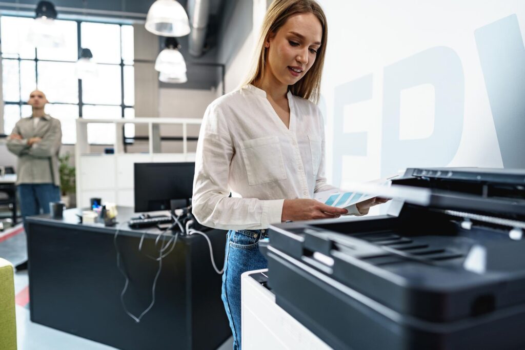 Young employee using modern printer in office