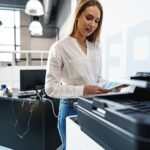 Young employee using modern printer in office