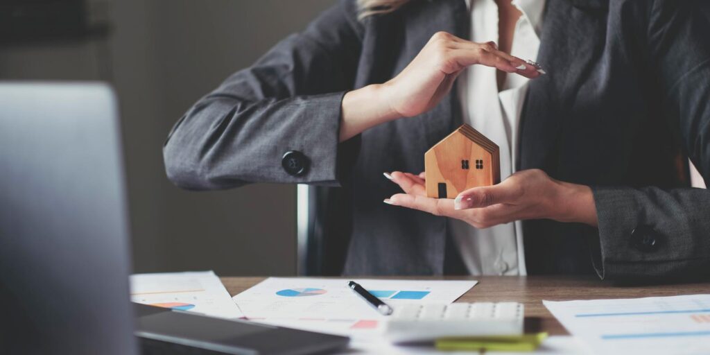 Female house insurance broker with a house model in her hand. House protection.