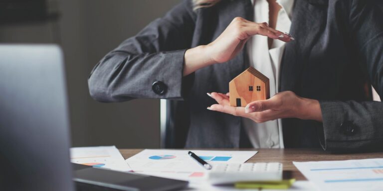 Female house insurance broker with a house model in her hand. House protection.